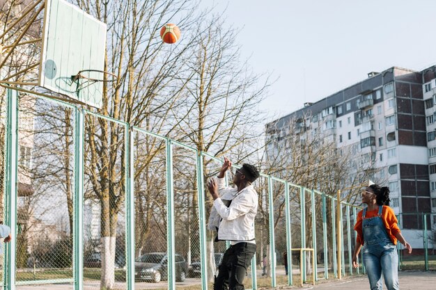 Счастливые подростки играют в баскетбол на улице