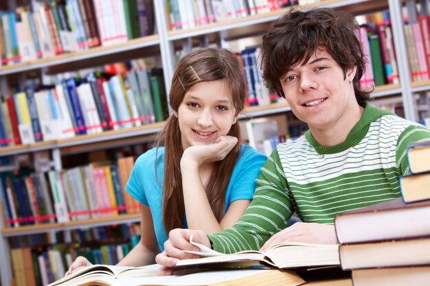 Happy teenagers with bookshelves background