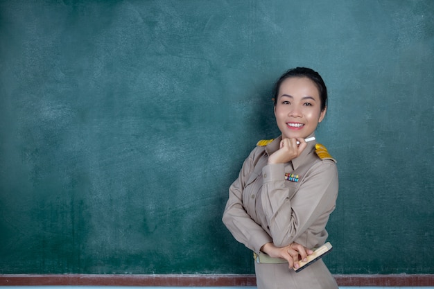 Happy thai teacher in official outfit  posing in front of  blackboard