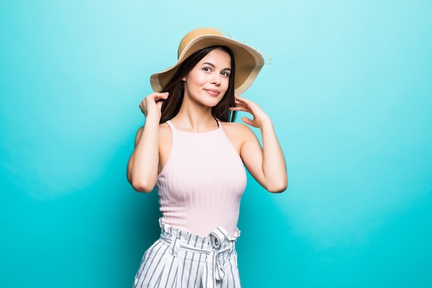 Happy thinking young woman looking up in straw hat on blue wall.