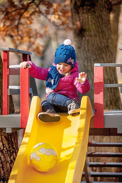 Free photo happy three-year baby girl in jacket on slide