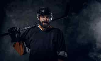 Free photo happy toothless hockey player is posing for photographer with hockey stick.