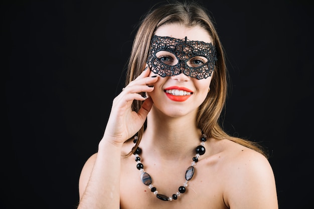 Felice donna in topless che indossa mascherata maschera di carnevale su sfondo nero