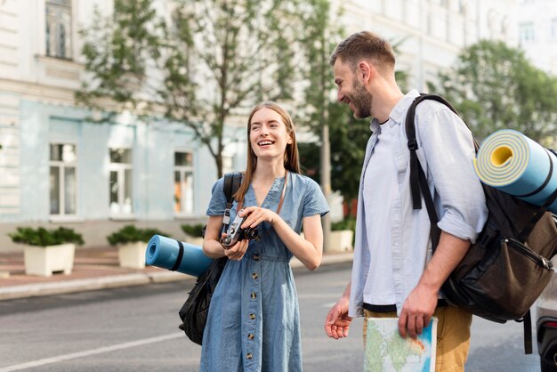 Happy tourist couple with camera and backpacks