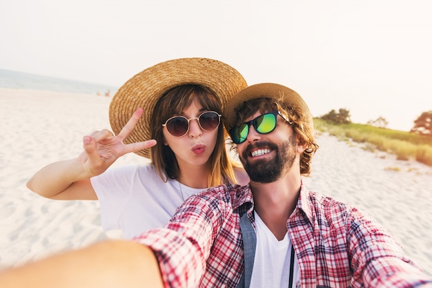Happy traveling couple in love taking a selfie on phone at the beach