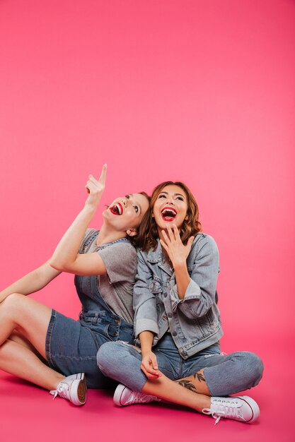 Happy two women friends pointing.