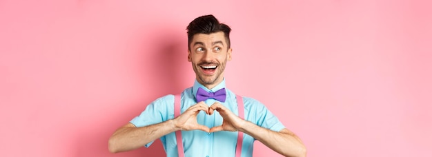 Free photo happy valentines day cheerful male model enjoying romantic date showing heart sign say i love you an