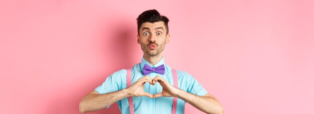 Happy valentines day funny young man waiting for lovers kiss pucker lips and show heart sign i love