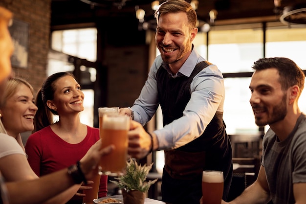 Счастливый официант раздает пиво своим клиентам, обслуживая их в баре