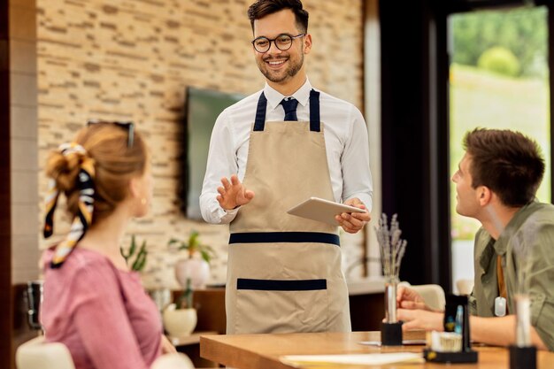 Happy waiter taking order from guests in a cafe