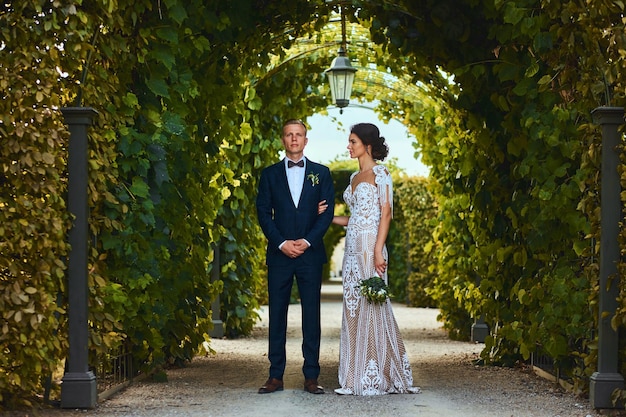 Счастливая свадебная пара гуляет по красивому саду.