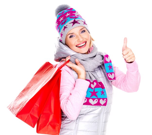 Happy white woman with shopping bags shows thumbs up sign isolated on white