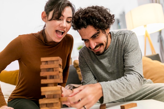 Happy wife and husband playing a wooden tower game