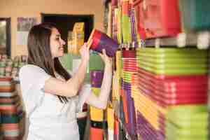 Free photo happy woman arranging colorful flowering plants in shelf