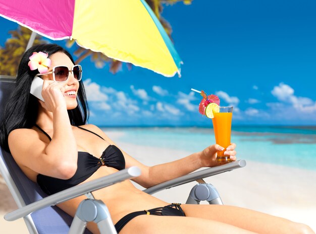 Happy  woman on the beach calling by mobile phone.