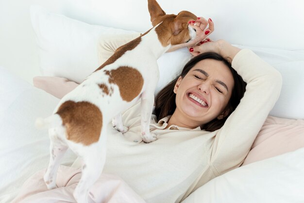 Happy woman in bed with her dog