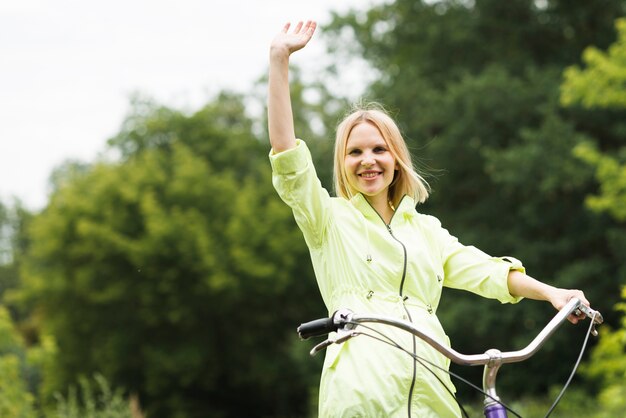 Happy woman on bicycle waving 