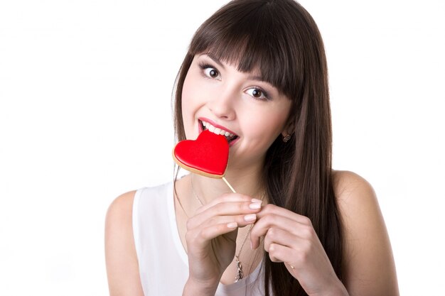 Happy woman biting heart shaped biscuit