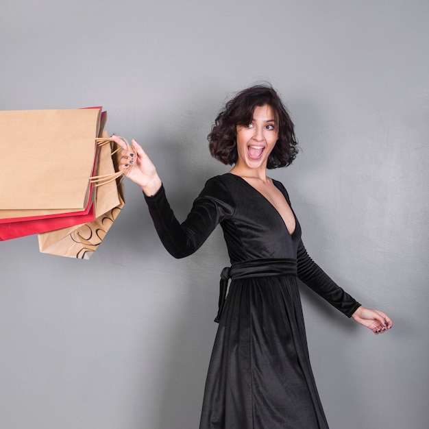 Foto gratuita donna felice in nero con borse della spesa