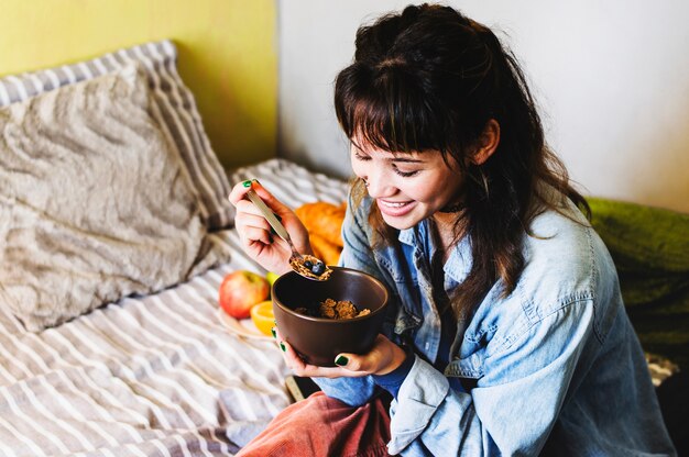 Happy woman breakfasting on bed