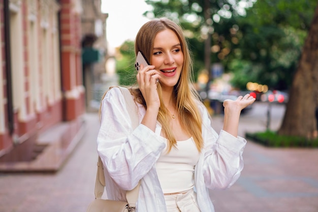 Happy woman call. Lifestyle outdoor portrait of pretty blonde woman speaking by her smatphone.