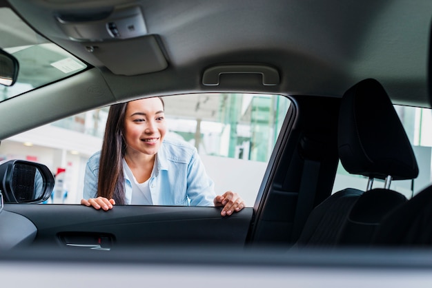 Happy woman in car dealership