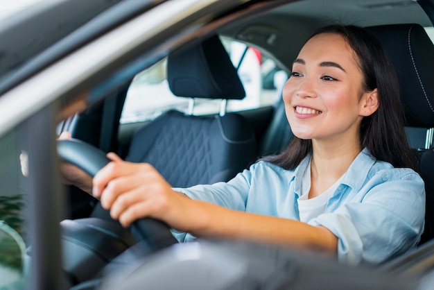 Happy woman in car dealership