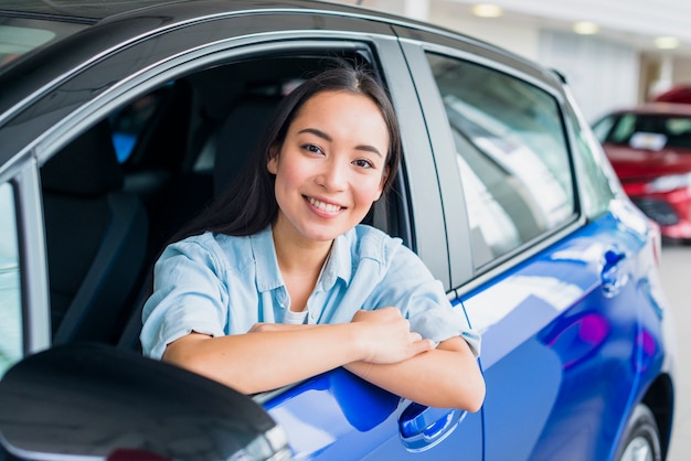 Happy woman in car dealership