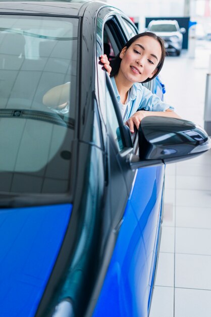 Happy woman in car dealership