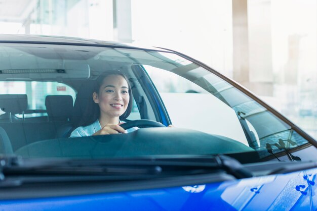 Happy woman in car dealership