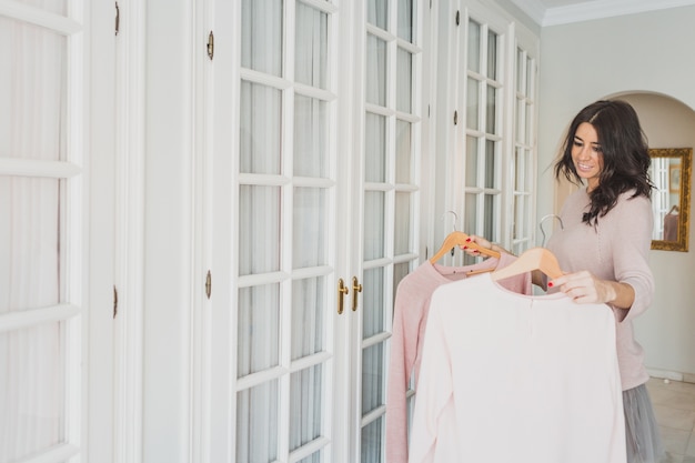 Happy woman choosing between two sweaters