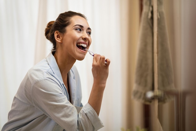 Happy woman cleaning her teeth with a toothbrush in the morning