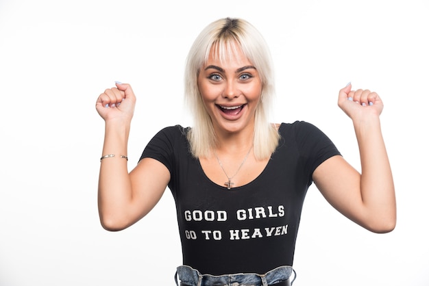 Happy woman closing her palms while laughing on white wall.