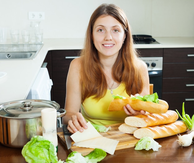 Free photo happy woman cooking sandwiches with cheese