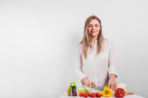 Happy woman cutting cabbage on wooden board