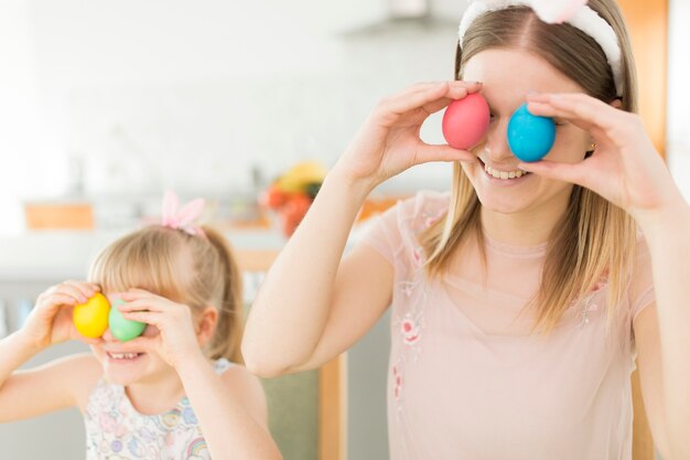 Happy woman and daughter posing with eggs