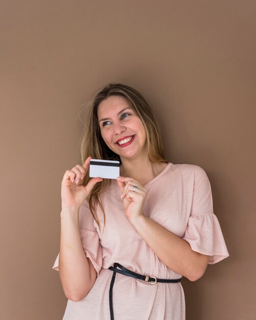 Happy woman in dress standing with credit card