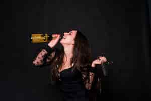 Free photo happy woman drinking champagne from bottle