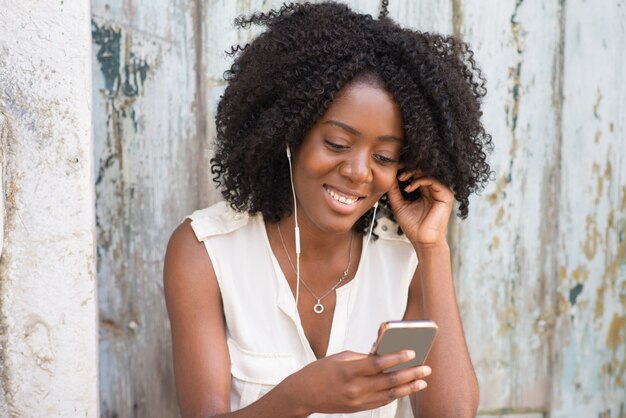 Happy woman in earphones enjoying music on phone