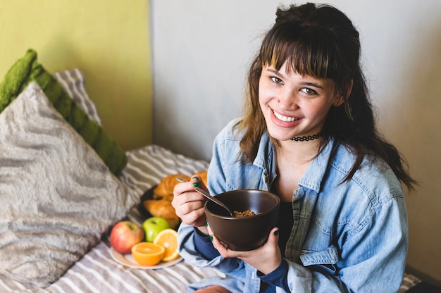 ベッドで食べる幸せな女性