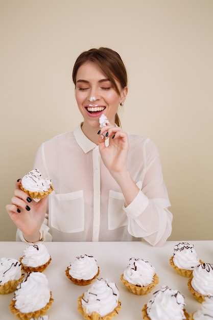 Free photo happy woman eating cupcakes at the table and having fun