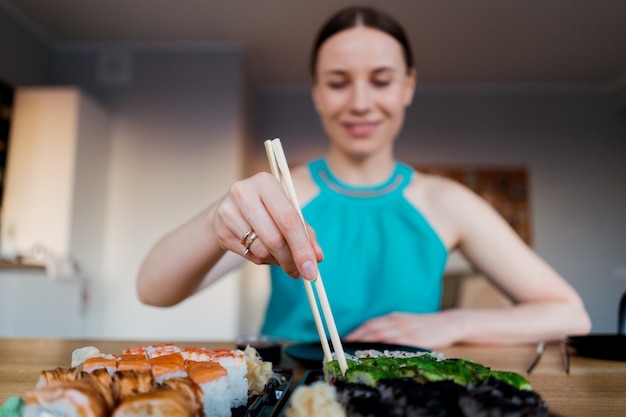 Happy woman eating delicious sushi