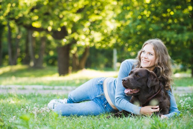 Счастливый женщина обнимает ее собаку в саду