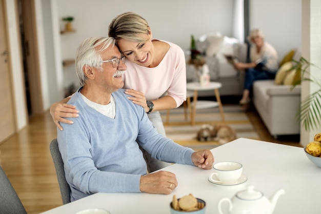 Happy woman embracing her senior father at home