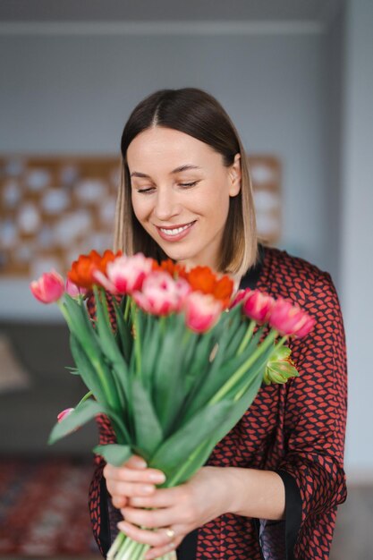 Happy woman enjoy bouquet of tulips Housewife enjoying a bunch of flowers and interior of kitchen Sweet home Allergy free
