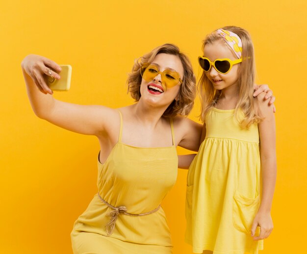 Happy woman and girl taking a selfie while wearing sunglasses