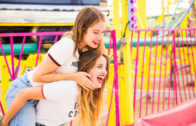 Happy woman giving piggyback to her female friend