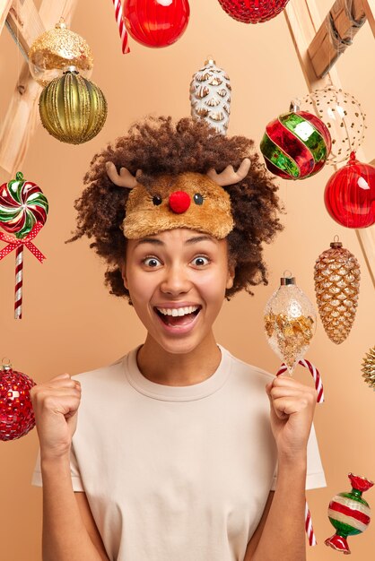 Happy woman glad to win New Year lottery raises clenched fists and exclaims with joy has good luck spends leisure time at home awaits for holidays or midnight stroke. Yeah finally feast is coming!