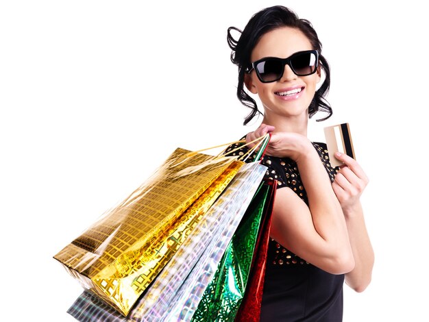 白い背景の上の購入とクレジットカードでメガネの幸せな女性。