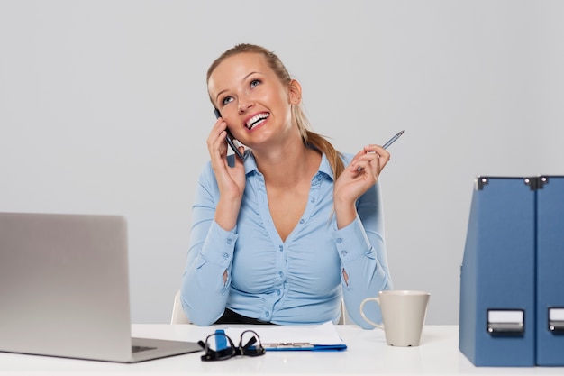 Happy woman gossiping on the phone in work